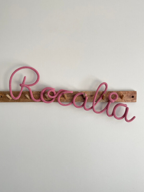 Imię ze sznurka Rozalia wisi na drewnianym wieszaku ściennym.