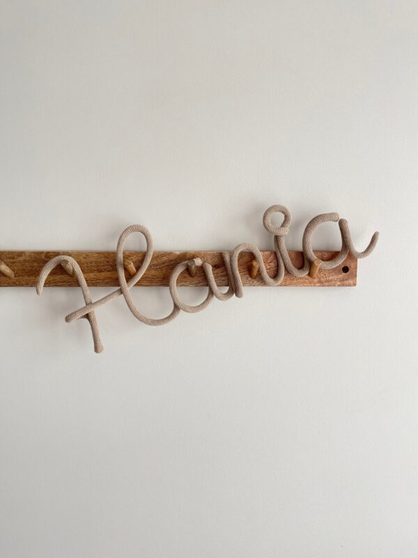 Imię ze sznurka Hania wisi na ścianie w pokoju dziecięcym.