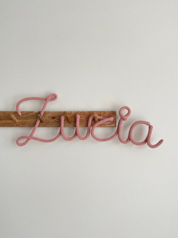 Imię ze sznurka dla dziewczynki Zuzia wisi na ścianie w pokoju dziecięcym.