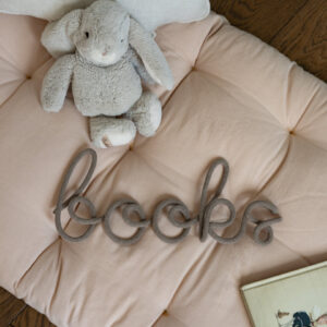 Napis ze sznurka books leży na materacu dziecięcym, a obok leży książka dla dzieci i pluszowy króliczek.