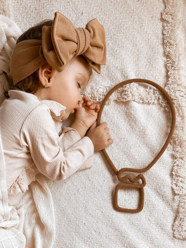 Mała dziewczynka śpi i w rączce trzyma balon dekorację ze sznurka.