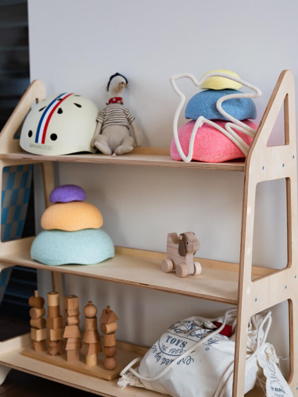 Zabawki dziecięce i ptaszek ze sznurka do dekoracji stoją na półce dziecięcej ze sklejki w pokoju dziecka.