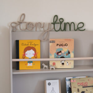 Napis ze sznurka storytime stoi na biblioteczce z książkami dla dzieci.