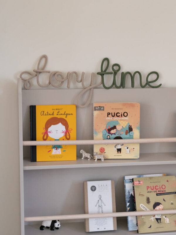 Napis ze sznurka storytime stoi na biblioteczce z książkami dla dzieci.