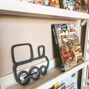 Dekoracja ze sznurka w kształcie pociągu stoi na półce z książkami dla dzieci.