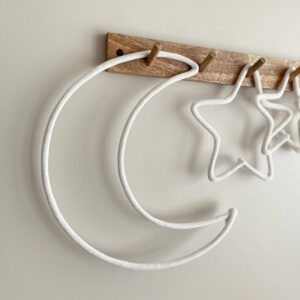 Ozdoba dziecięca w kształcie księżyca wisi z gwiazdkami ze sznurka na drewnianym wieszaku ściennym.